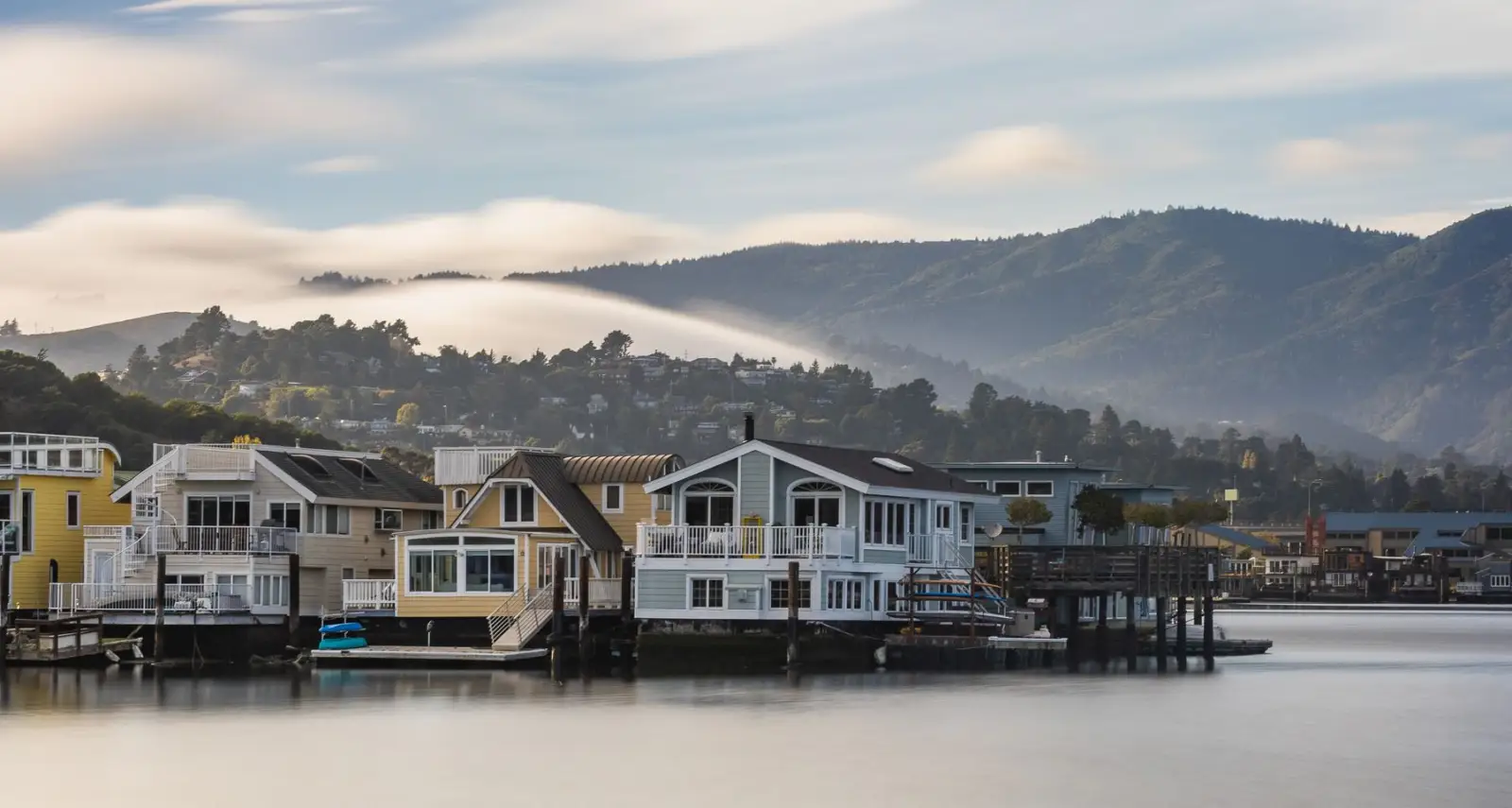 Sunny day on the waterfront in Sausalito, California — houseboats, green hills, and open sky